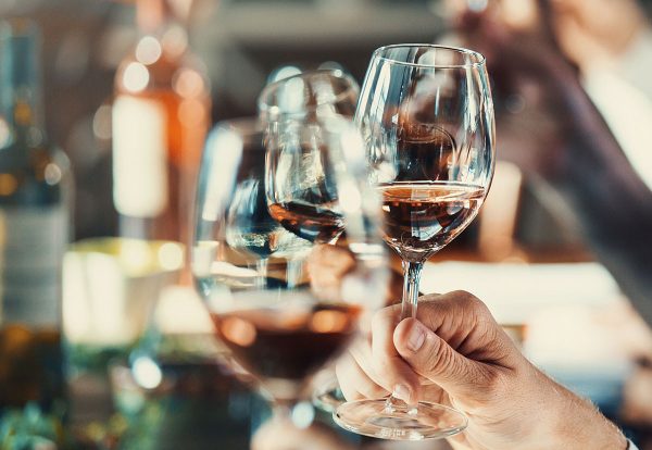 Hands holding glasses of red wine at tasting.