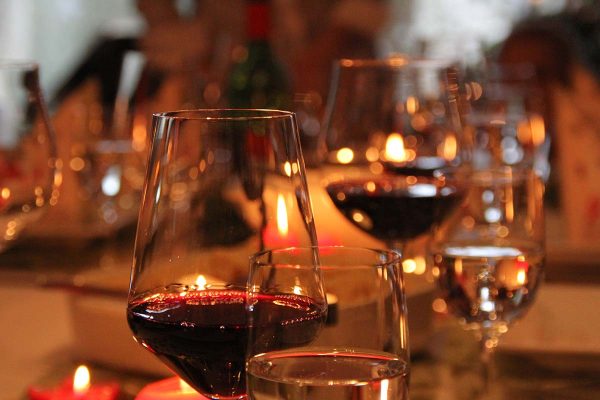 Candlelit table with glasses of red wine.